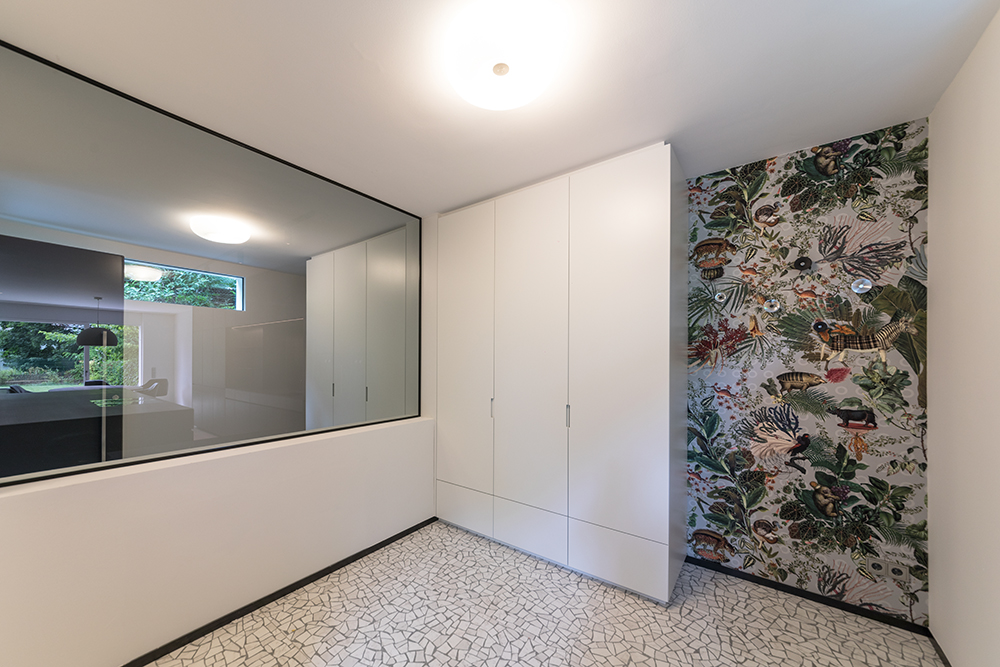 Badezimmer mit hellem Einbauschrank, Glasdusche und dekorativer Wandgestaltung