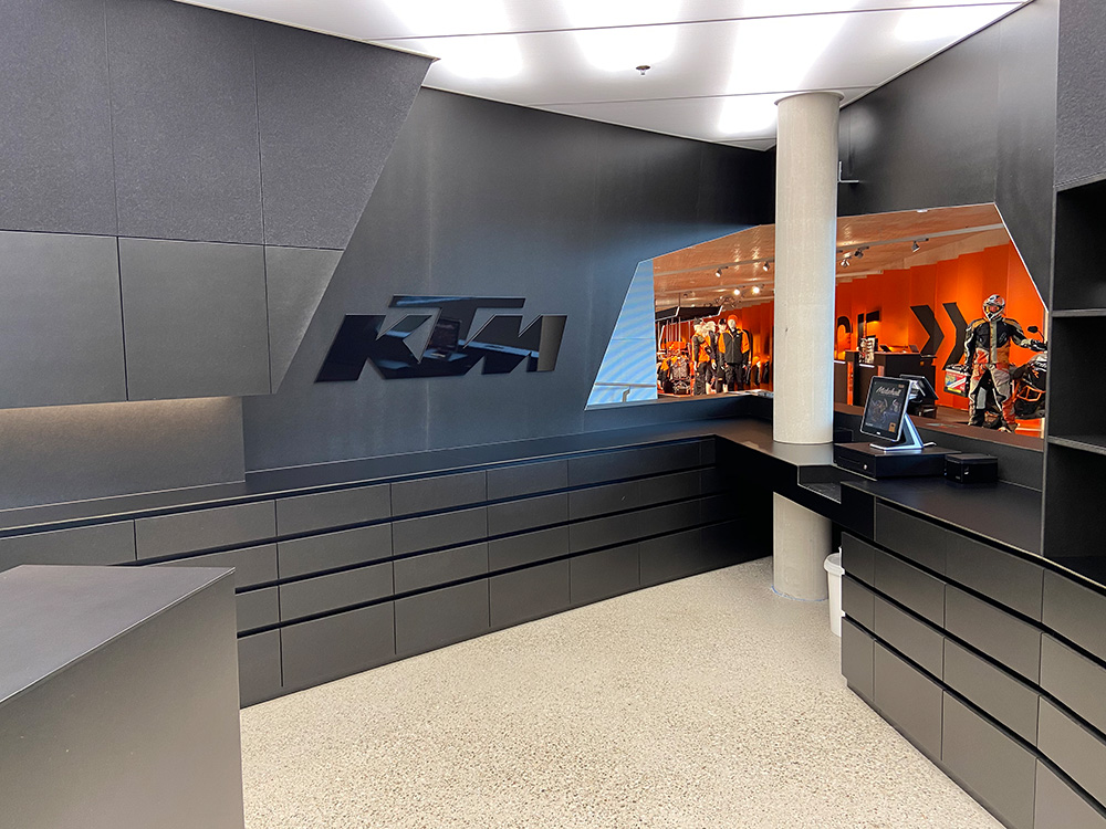 Empfangsbereich der KTM Motorhall mit schwarzer Theke und grauer Wandgestaltung