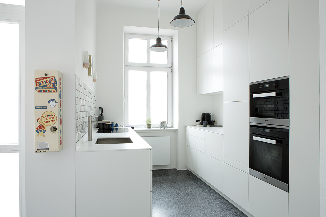 Küchenansicht mit Spüle, weißen Fronten und Hängeleuchten im Projekt Kitchen Liniengasse Wien