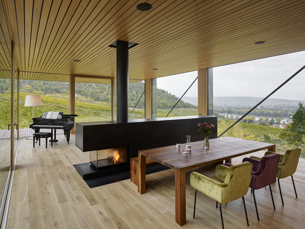 Innenraum mit Panoramafenster, Holzelementen und Blick auf die Weinlandschaft